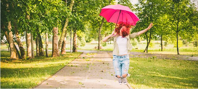 woman jumping with a pink umbrella