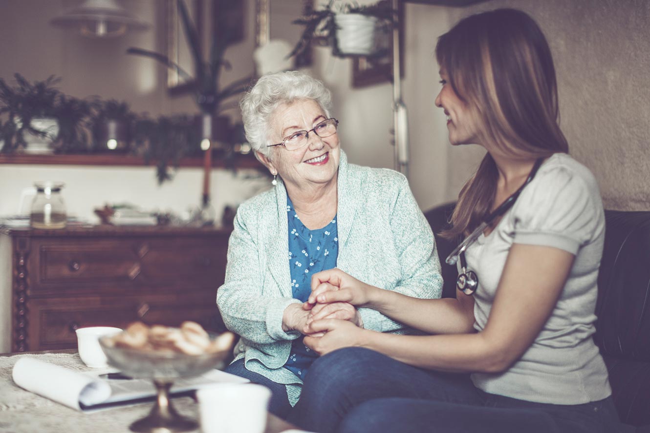 woman and elderly woman smiling at each other